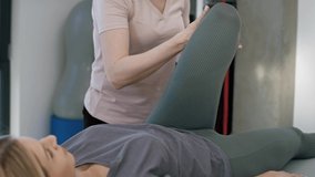 Female physical therapist helping her patient with leg problem. Shot with RED helium camera in 8K. 
