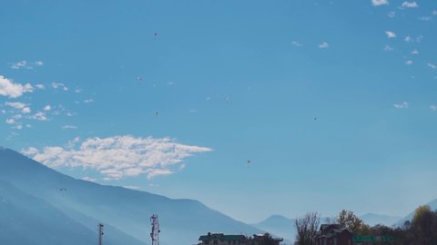 Group of people paragliding with parachute in front of the mountains at Manali in Himachal Pradesh, India. Tourists enjoying paragliding during their holidays. Adventure activities in the mountains. 