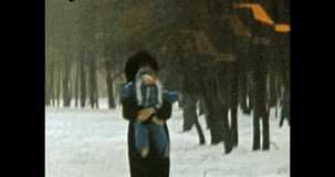 Funny little child with mother in sunny winter forest. Baby in blue clothes runs by snow park. Happy parents, child in family life. Lifestyle outdoors. Vintage color film. Family archive. Retro 1980s