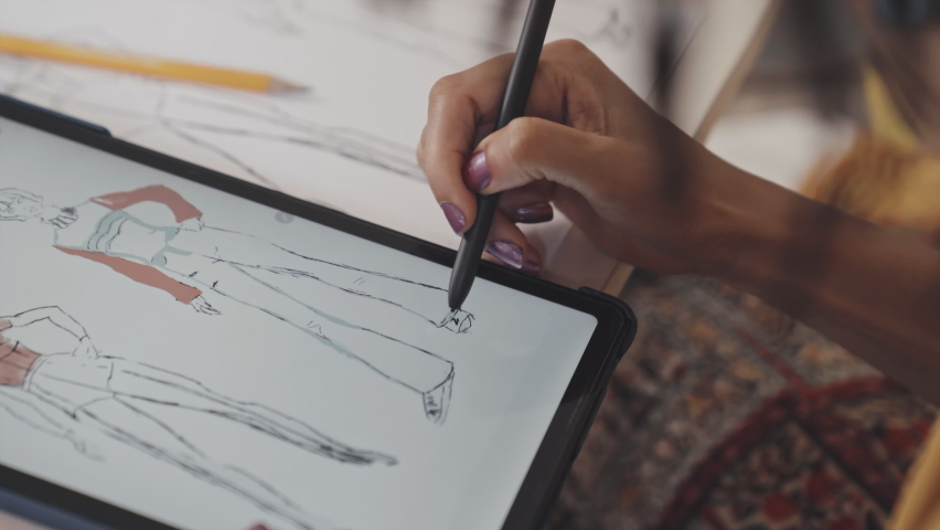 Close up over the shoulder shot of hands of black female designer drawing fashion sketch on paper | Shutterstock HD Video #1090976167