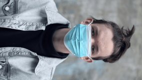 Vertical video. Teen boy putting medical protective face mask looking at camera. Coronavirus prevention - Powered by Shutterstock - Get 15% off with code: PIKWIZARD15