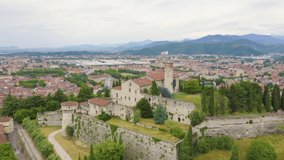 Inscription on video. Brescia, Italy. Castello di Brescia. Flight over the city in cloudy weather. Multicolored text appears and disappears, Aerial View, Point of interest