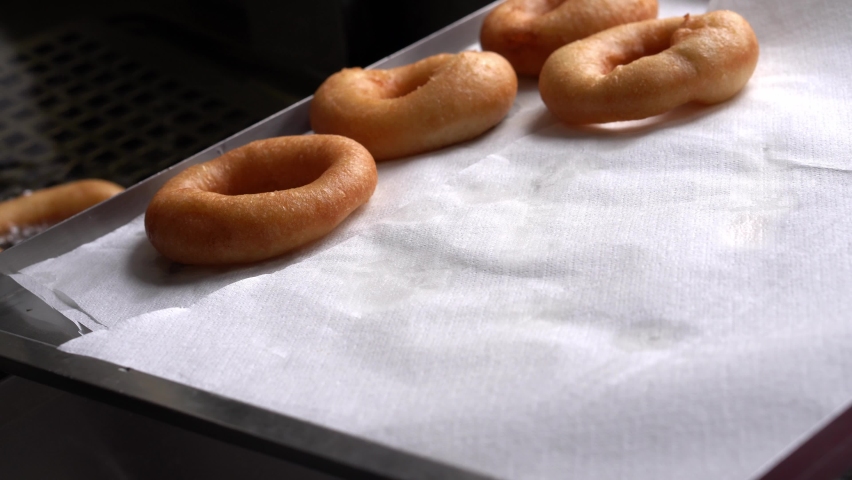 Chef puts fresh crispy donuts on paper towels. Cooking tasty donuts in cafe. Close-up fast-food Royalty-Free Stock Footage #1090988171