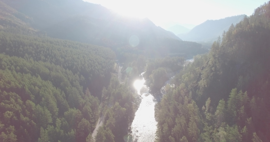 4K aerial point of view. Low altitude flight over fresh fast mountain river with rocks at sunny summer morning. Green pine trees and sun rays. Raw colors, no color correction. Royalty-Free Stock Footage #1090988715