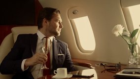 Smiling entrepreneur relaxing jet closeup. Attractive drink champaign sunlight. Rich handsome man confident company executive look watch talk partner wife on corporate trip. Wealthy lifestyle concept - Powered by Shutterstock - Get 15% off with code: PIKWIZARD15