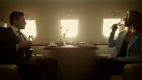 Luxury couple flying jet in golden sunlight. Successful business partners rest celebrate contract deal on corporate trip. Confident gentleman have dinner with beautiful lady. Wealthy lifestyle concept - Powered by Shutterstock - Get 15% off with code: PIKWIZARD15