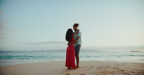 Beautiful aspirational young couple enjoying romantic sunset walk on the beach on vacation