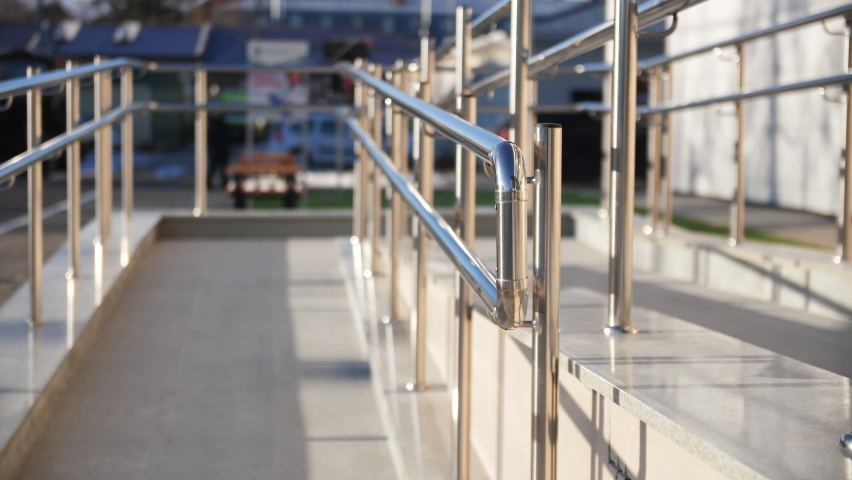 Empty ramp with shiny metal railings for handicapped people near public building entrance on sunny day close view Royalty-Free Stock Footage #1090997519