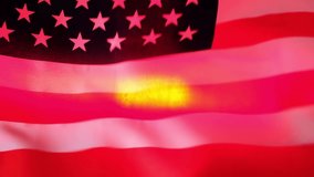 Video of police flasher light shines through the American flag waving on the wind. USA flag with red and blue flashing lights.