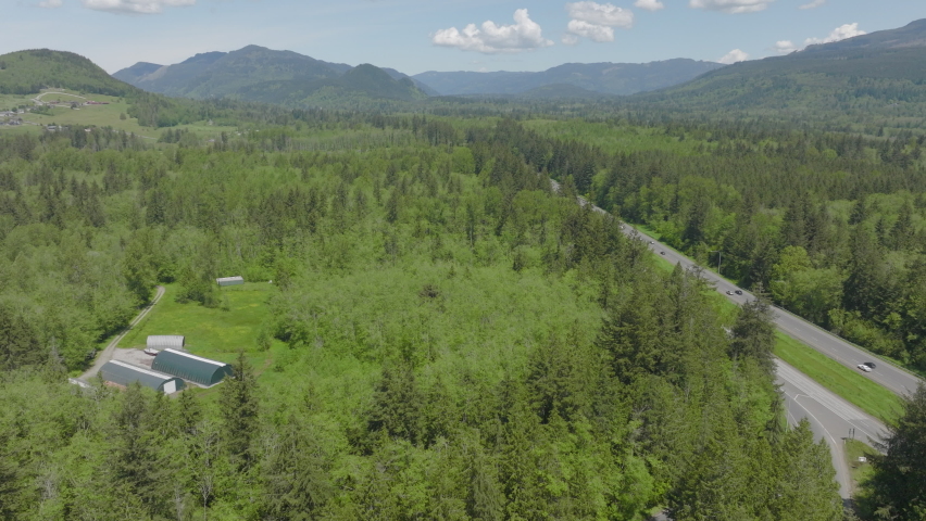 Aerial of Bellingham, Washington pushing alongside highway and towards mountains and foothills.