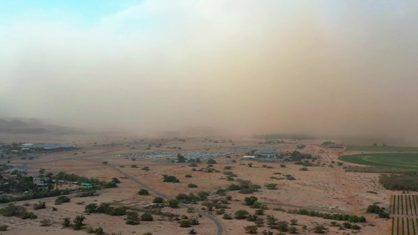 Large dark sandstorm moves over Timna Park in the Negev Desert as the sky above the storm is a bright blue. High drone dolley shot