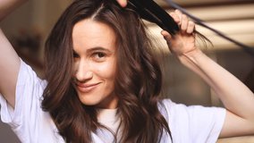 Happy brunette woman make curl hair using flat iron. Funny girl does herself hair styling. Makes curls with curling irons and show curl. Woman shoot her video blog about hair care and style. - Powered by Shutterstock - Get 15% off with code: PIKWIZARD15
