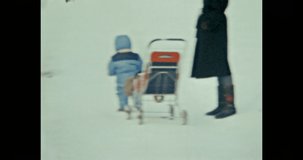 Mother and small child in winter park relax, spend time together. Woman with child dressed in warm clothes on frosty forest outdoors. Family lifestyle. Vintage color film. Family archive. Retro 1980s