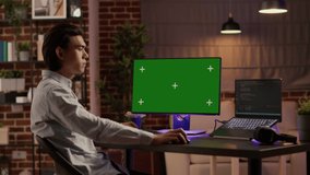 Asian businessman looking at computer with greenscreen on display, analyzing isolated copyspace with mockup template, chroma key and blank background, network technology. Tripod shot. - Powered by Shutterstock - Get 15% off with code: PIKWIZARD15