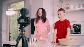 Boy and girl recording culinary blog at home. Children greet their spectators.