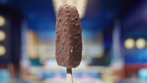 Chocolate ice cream on a stick rotating in slow motion. Ice cream with chocolate glaze with nuts.