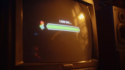 Close Up Footage of a Retro TV Set Screen with an Eight Bit Eighties Inspired Console Arcade Video Game. Quest Loading, Player Kills a Monster, Collects Hearts and a Treasure Chest, and Wins.