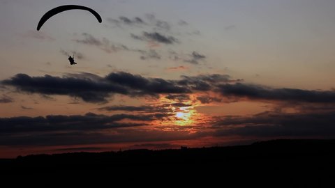 tandem paraglider landing on sunset background