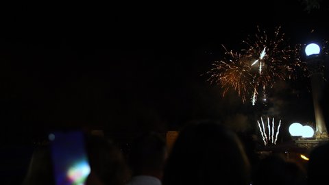 Shoots fireworks video on smartphone, hand of man taking the photo of fireworks by smartphone. Shoots fireworks on a smartphone. The lights are beautifully reflected in phone screen.