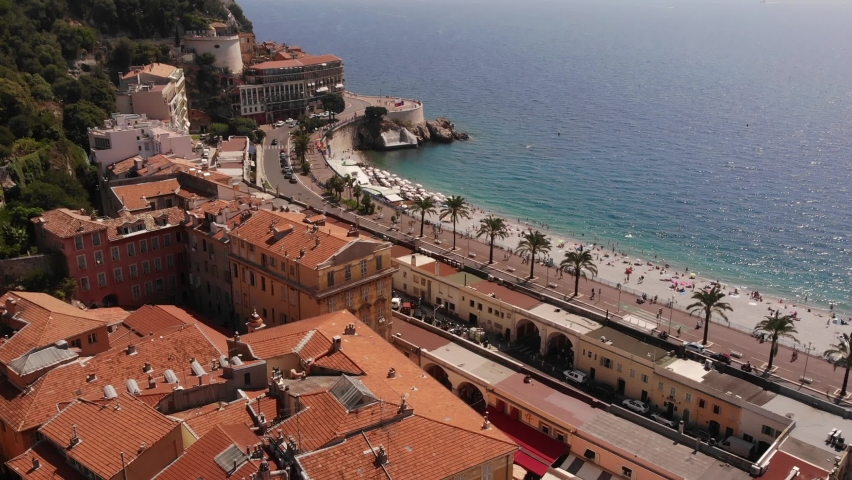 Beautiful panorama of English Promenade in Nice. Palm trees, old houses with tiles on the roof. Azure sea and green hill. Summer in the French Riviera. View from the sky. video shooting from drone | Shutterstock HD Video #1091020907