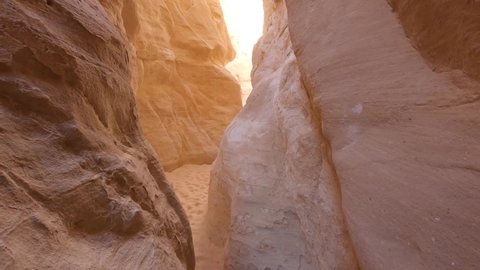 Narrow gorge between two high rocky colored orange mountains in Egypt Canyon site. Pan up to bright sky