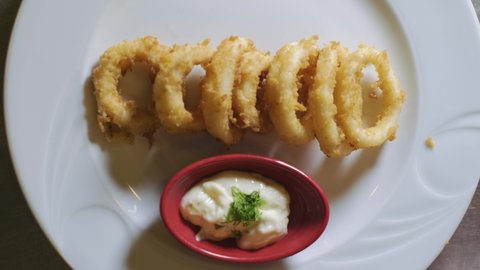 Delicious and tasty fried calamari squid rings on plate, calamari. The chef is putting the fried squids on the plate. slow motion.4K