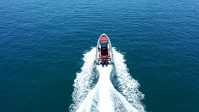 Aerial drone tracking video of inflatable rib speed boat cruising in high speed in deep blue open ocean sea