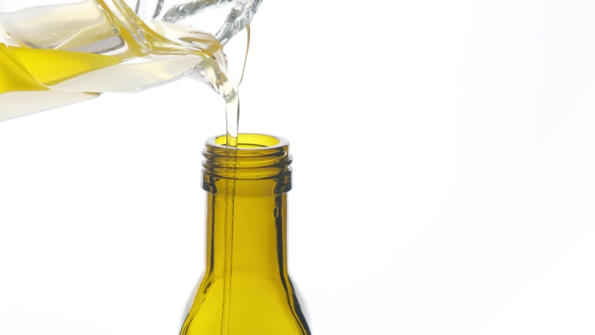 Vegetable oil is poured into a bottle on a white background close-up. Royalty-Free Stock Footage #1091042917