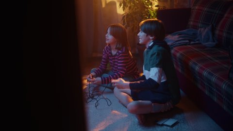 Nostalgic Childhood Concept: Young Boy and Girl Playing Arcade Video Game on a Retro Gaming Console at Home in a Room with Period-Correct Interior. Kids Win the Level and High Five.