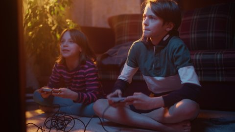 Nostalgic Childhood Concept: Young Brother and Sister Playing Arcade Video Game on a Retro Console in a Living Room with Period-Correct Interior. Friends Spend the Day at Home Playing Games.