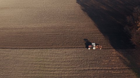 Tractor plowing agricultural fields, aerial view from drone