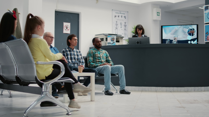 Diverse group of people waiting in hospital reception lobby to attend medical appointment with general practitioner. Patients in waiting room lobby sitting at healthcare clinic. Tripod shot. | Shutterstock HD Video #1091046913
