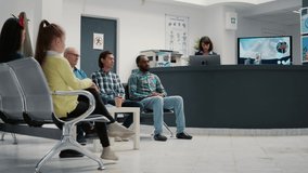 Diverse group of people waiting in hospital reception lobby to attend medical appointment with general practitioner. Patients in waiting room lobby sitting at healthcare clinic. Tripod shot. - Powered by Shutterstock - Get 15% off with code: PIKWIZARD15