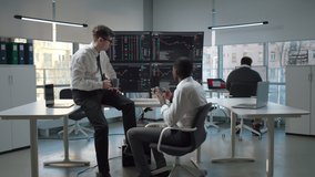 Diverse traders drink coffee and discuss stock market sitting in modern open space office. Programmers relax having coffee break - Powered by Shutterstock - Get 15% off with code: PIKWIZARD15