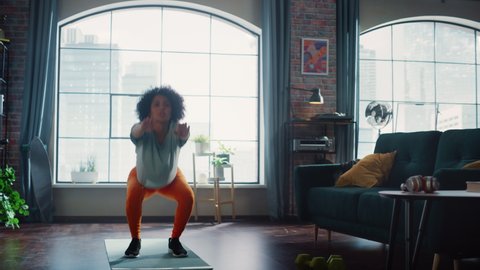 Serious Multiracial Female Doing Butt Workout Squats at Home. Athletic Motivated Woman Training to Have Beautiful Body. Fitness at home concept. Establishing Shot