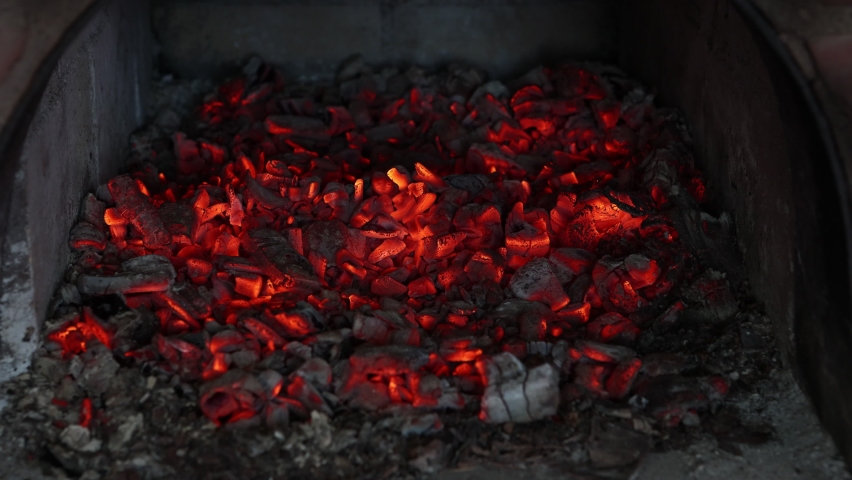 Poker stirs glowing coals in wood-burning stove. Royalty-Free Stock Footage #1091051659