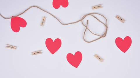 Stop motion red paper hearts fixed with clothespins on a cord. White background. Space for copy.