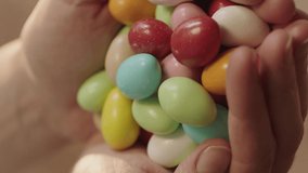 Close-up view of colored candies or chewing gum.Woman holding a pile of Colorful candies or chewing gum.Video for the vertical story.