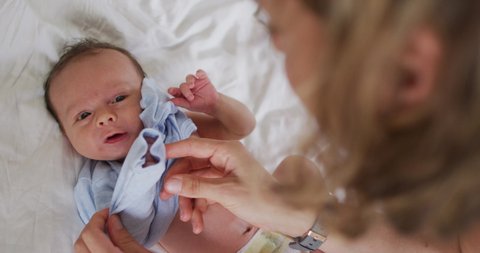 Video of hands of caucasian mother taking care of newborn baby. motherhood, parental love and taking care of newborn baby concept digitally generated video.