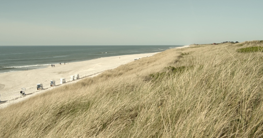 Wide angel shot of the beach and the dunes of Sylt with the Northsea in the background 4k 60fps