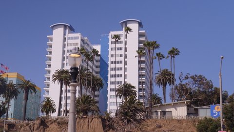 Panning shot of cliffside hotel off Ocean avenue in Santa Monica. Palm trees swaying in the wind right on the beachfront property. Perfect transition shot.
