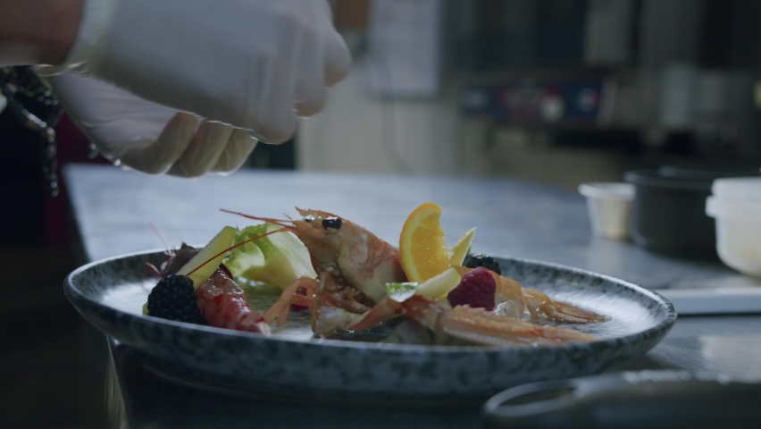 A professional Italian chef is preparing a tasty fish plate with scampi, salad and fruits - 02