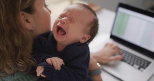 Video of caucasian mother working on laptop from home with newborn baby. motherhood, parental love and taking care of newborn baby concept digitally generated video.