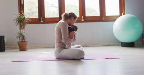 Video of caucasian mother and newborn baby on yoga mat. motherhood, parental love and back to shape concept digitally generated video.
