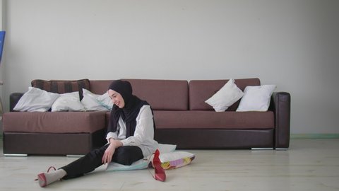 Young Muslim woman trying on red high heel shoes. Fashion