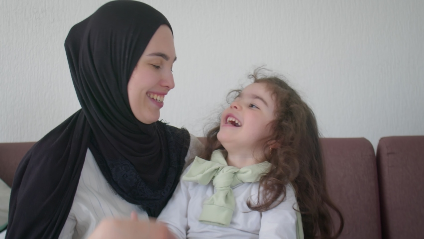Close-up Mom and daughter are having fun on the sofa. Muslim family