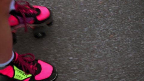 A young attractive girl in a pink bodysuit rides pink retro quad roller skates. Roller close-up, urban city. Sports girl on roller skates. Hobbies, sports, summer. วิดีโอสต็อก