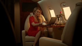 Attractive businesswoman having video call on corporate first class trip alone. Successful executive using computer talking lawyer partner online on private jet. Business professional at work concept.