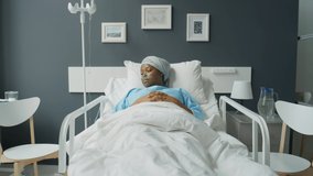 Zoom in shot of young African American female patient with nasal cannula and headwrap lying on bed in hospital ward, looking at side and then posing for camera - Powered by Shutterstock - Get 15% off with code: PIKWIZARD15