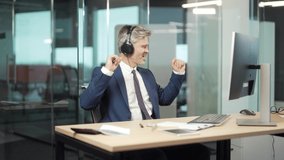 Mature businessman worker listening music in office at computer desk Cheerful senior gray hair business man in headphones relaxes, dances sings. Enjoy. Funny Employee Entrepreneur in Workplace at work - Powered by Shutterstock - Get 15% off with code: PIKWIZARD15